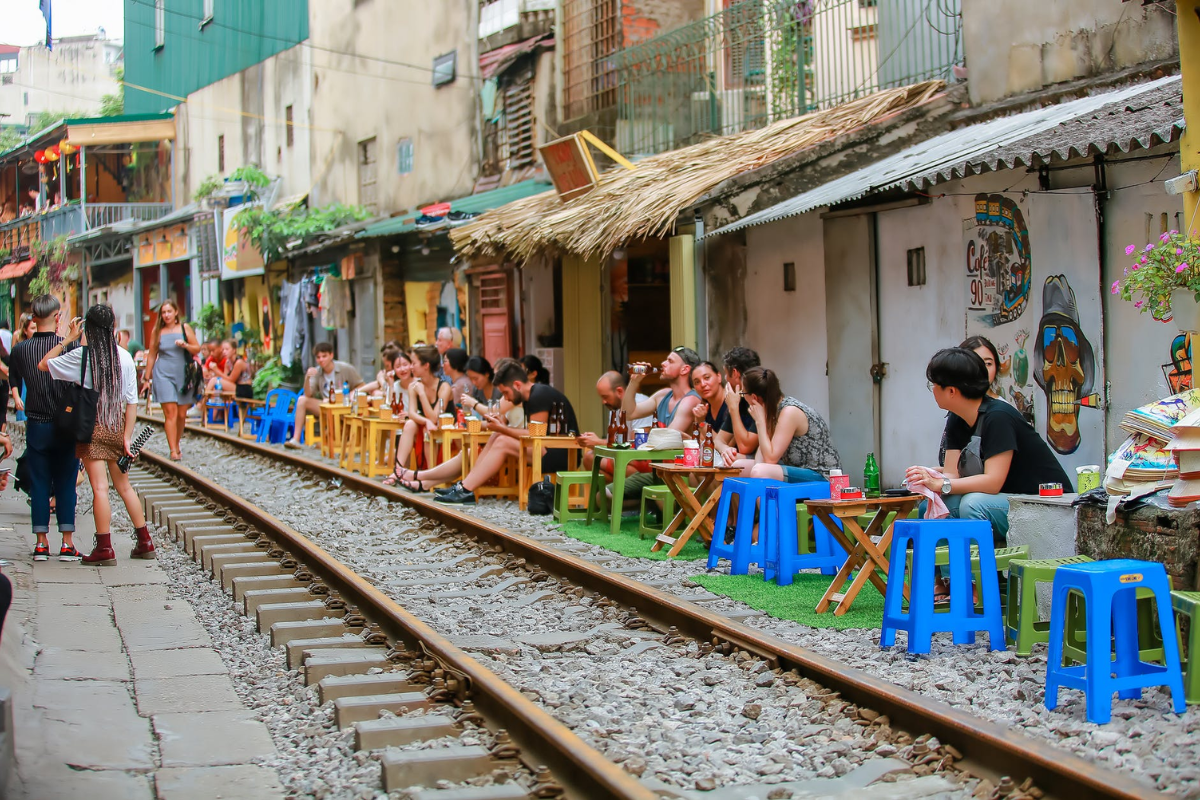 Daily life of locals along Hanoi Train Street with people chatting and selling food